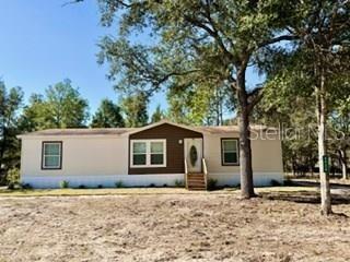 A single-story manufactured home with beige siding and a brown accent wall sits outdoors — 2629 NW 29TH TERRACE, BELL, FL