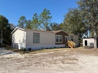 A single-story manufactured home with light siding and a small wooden porch stands outdoors — 2629 NW 29TH TERRACE, BELL, FL