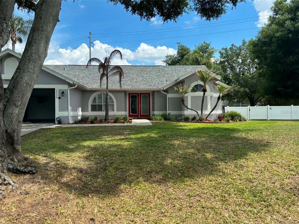 A single-story gray house with a red double front door and a large front lawn — 5358 MONTSERRAT DRIVE, LAKELAND, FL