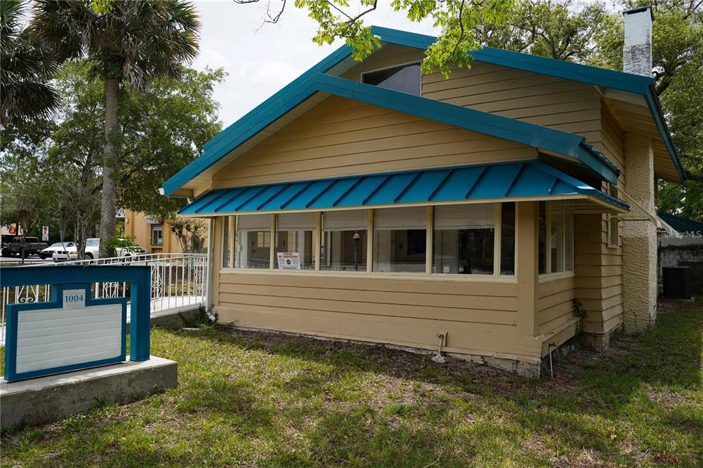 A tan house with blue trim and a metal awning over a front porch — 1004 TALTON AVENUE, DELAND, FL