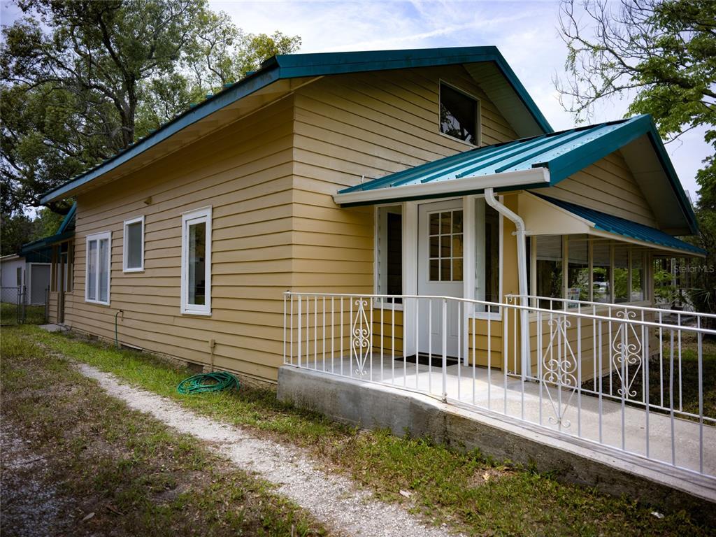 A yellow house with a teal metal roof and a white metal porch railing — 1004 TALTON AVENUE, DELAND, FL