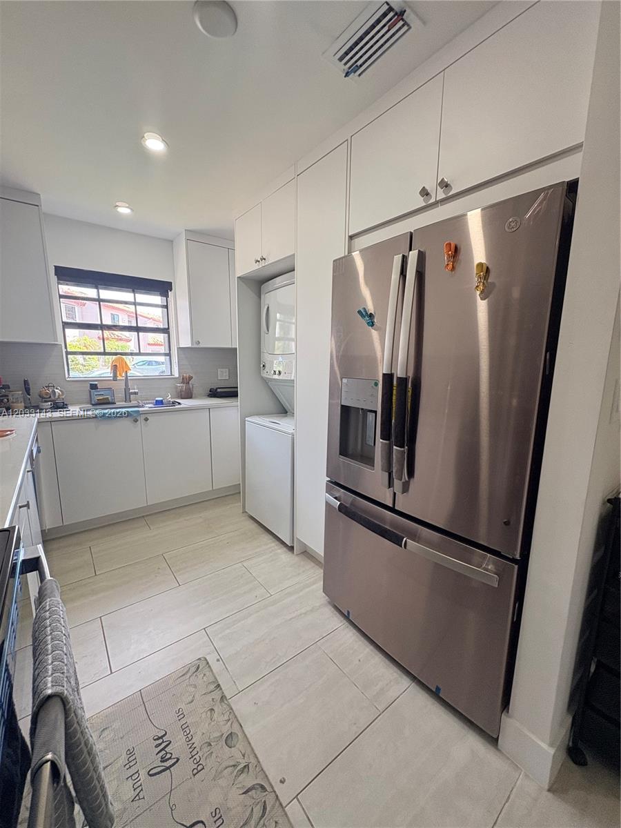 A modern kitchen features white cabinets, quartz countertops, and a light-colored tiled backsplash — 15430 SW 74th Cir Ct # 501, Miami FL 33193, MIAMI, FL