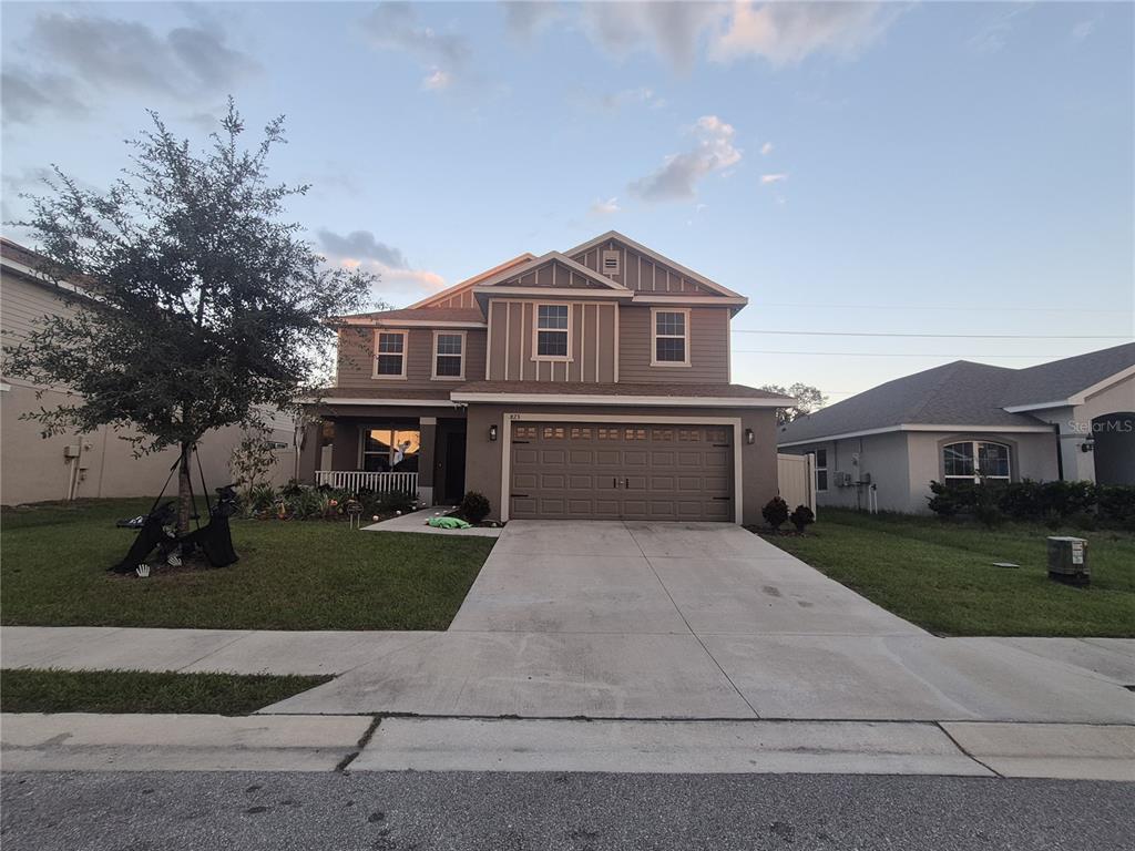 A covered porch features two gray rocking chairs, a potted plant, and a doorbell button — 823 CHINOY ROAD, DAVENPORT, FL