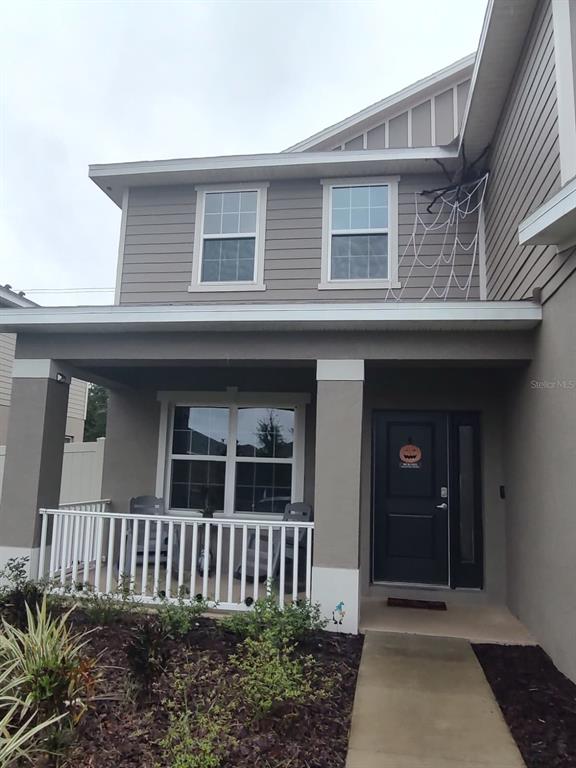 A two-story house with a gray exterior, a two-car garage, and a white vinyl fence — 823 CHINOY ROAD, DAVENPORT, FL