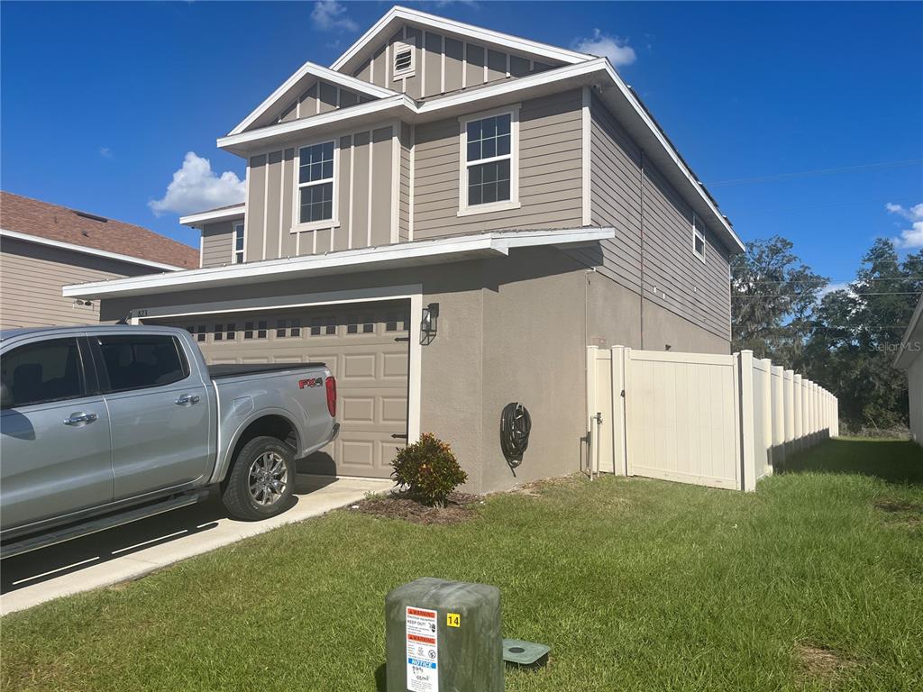 The backyard features a grassy lawn, a concrete patio, and a two-story house exterior — 823 CHINOY ROAD, DAVENPORT, FL