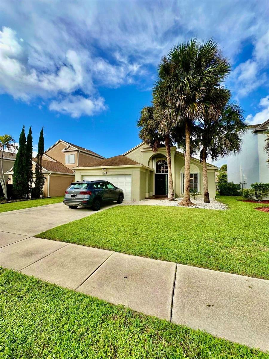 A single-story house with a green exterior, a two-car garage, and palm trees in front — 22449 Middletown Drive, Boca Raton FL 33428, BOCA RATON, FL