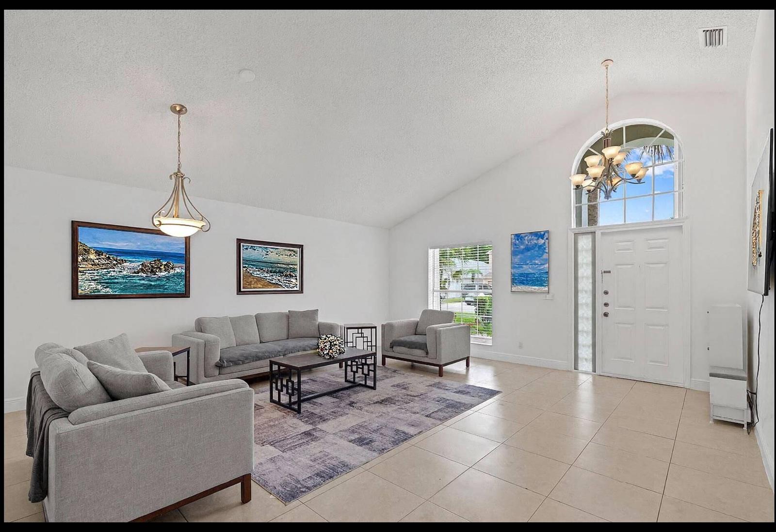 A living room with light tile floors, grey furniture, a patterned rug, and vaulted ceilings — 22449 Middletown Drive, Boca Raton FL 33428, BOCA RATON, FL