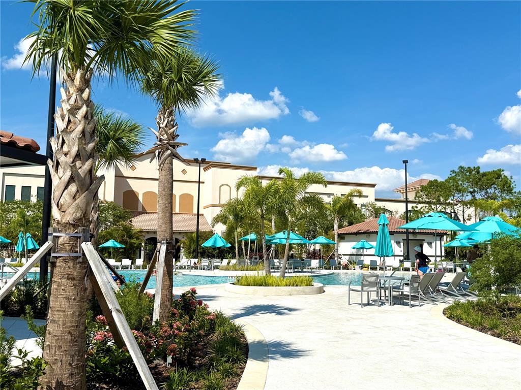 A swimming pool area features palm trees, blue umbrellas, and a multi-story building exterior — 4024 BREAKVIEW DRIVE UNIT 105, ORLANDO, FL
