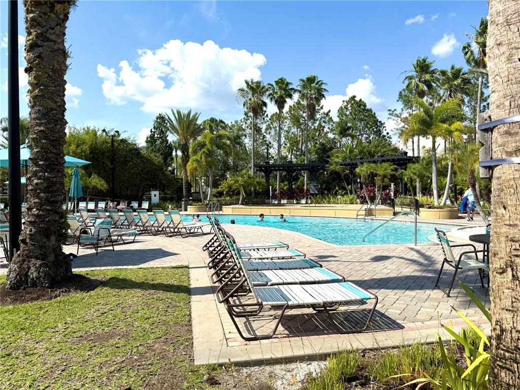 A swimming pool surrounded by lounge chairs, palm trees, and a paved patio area — 4024 BREAKVIEW DRIVE UNIT 105, ORLANDO, FL