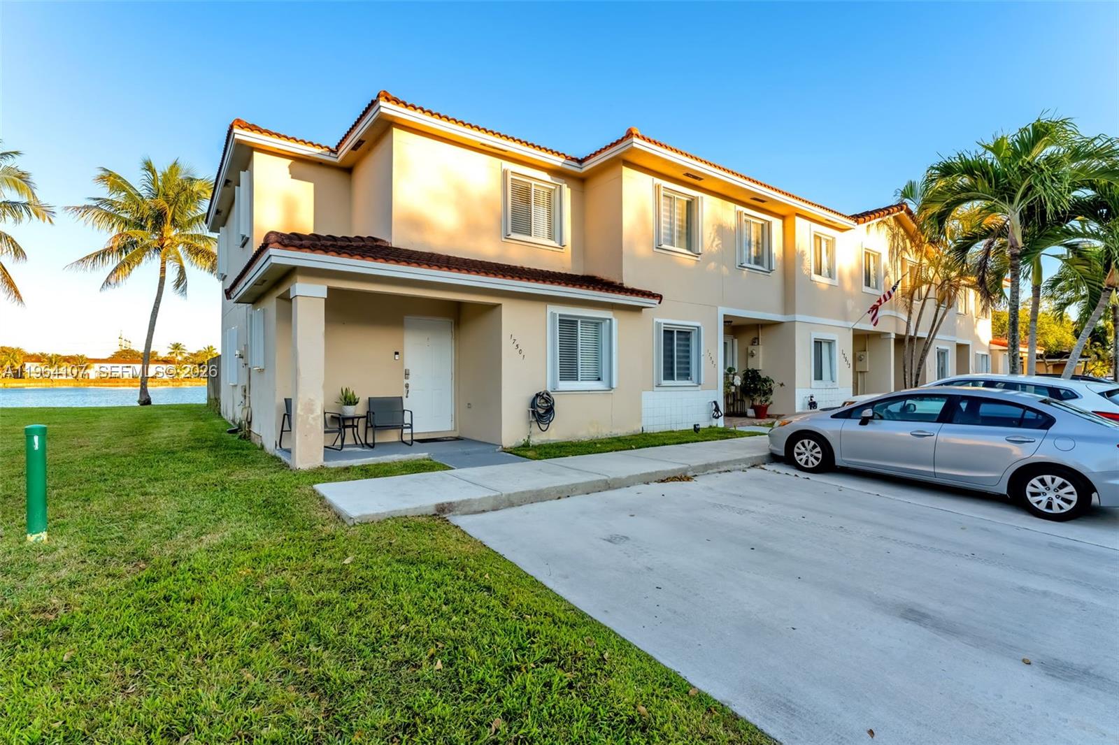A two-story tan townhouse with a tiled roof sits beside a lake and parking area — 17501 SW 140th Ct, Miami FL 33177, MIAMI, FL