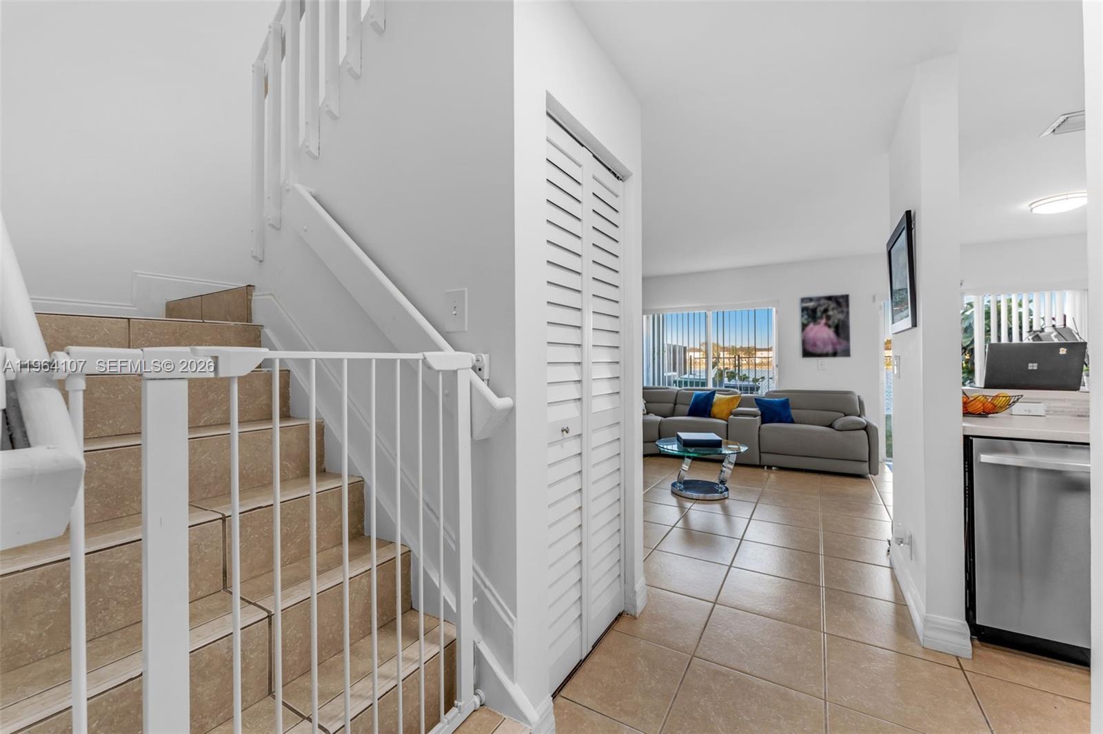 A tiled staircase with a safety gate leads to an open living area with tile floors — 17501 SW 140th Ct, Miami FL 33177, MIAMI, FL