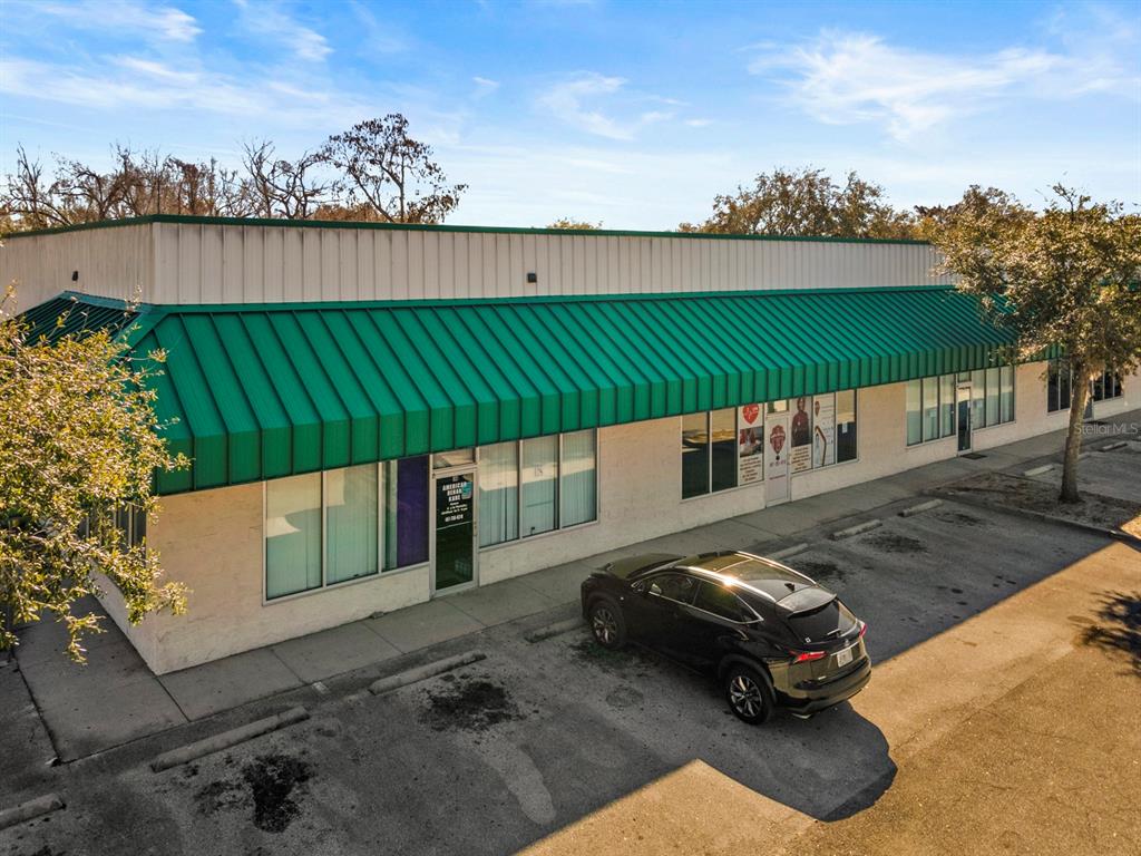 A single-story commercial building with a green metal awning and a parked black SUV — 3239 OLD WINTER GARDEN ROAD UNIT 13, ORLANDO, FL