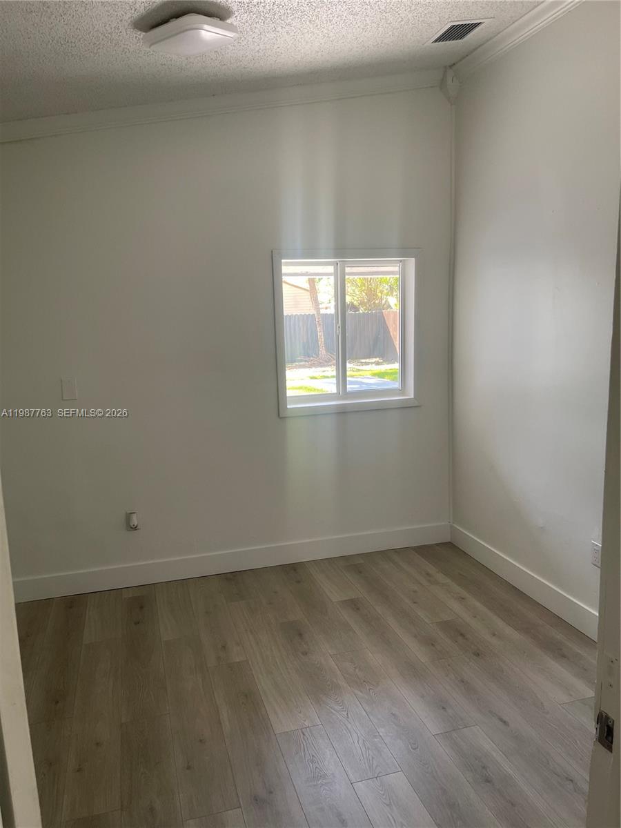 A small, empty room features white walls, light wood-look flooring, and a single window — 20700 SW 122nd Ave, Miami FL 33177, MIAMI, FL