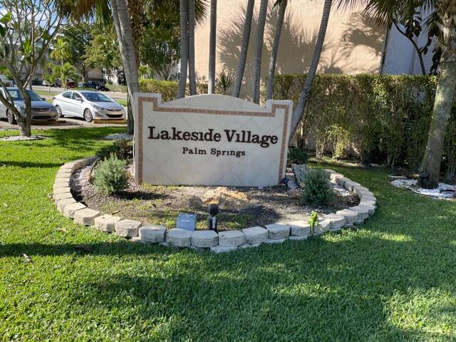 A stone sign for Lakeside Village Palm Springs sits in a landscaped garden bed — 705 Lori Drive # 315, Palm Springs FL 33461, PALM SPRINGS, FL