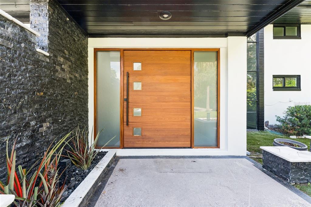 A modern wooden front door with four square windows is flanked by frosted glass sidelights — 5583 JESSAMINE LANE, ORLANDO, FL
