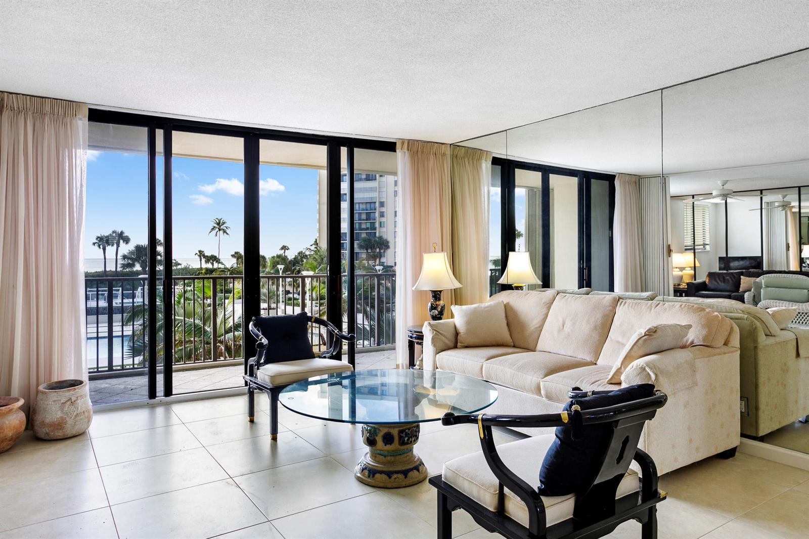 A living room with tile floors, a glass coffee table, and a mirrored wall — 200 Ocean Trail Way # 106, Jupiter FL 33477, JUPITER, FL