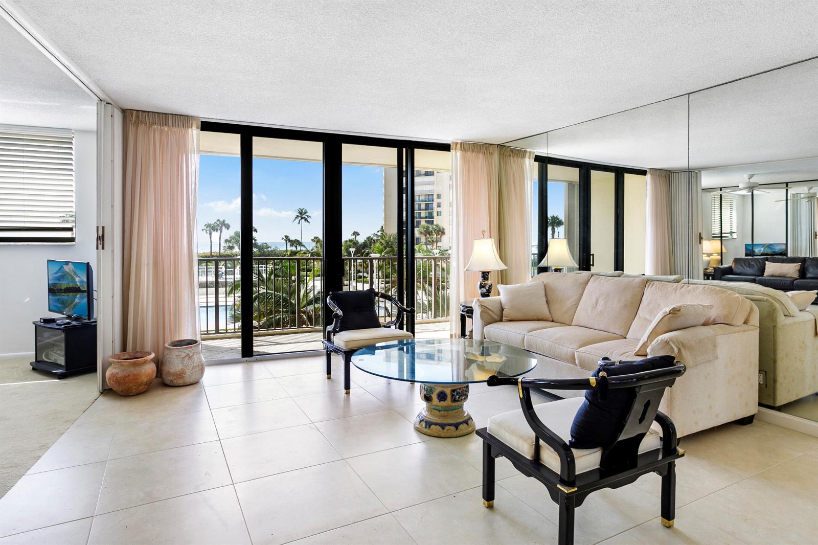 A living room features tile floors, a glass coffee table, and sliding doors to a balcony — 200 Ocean Trail Way # 106, Jupiter FL 33477, JUPITER, FL