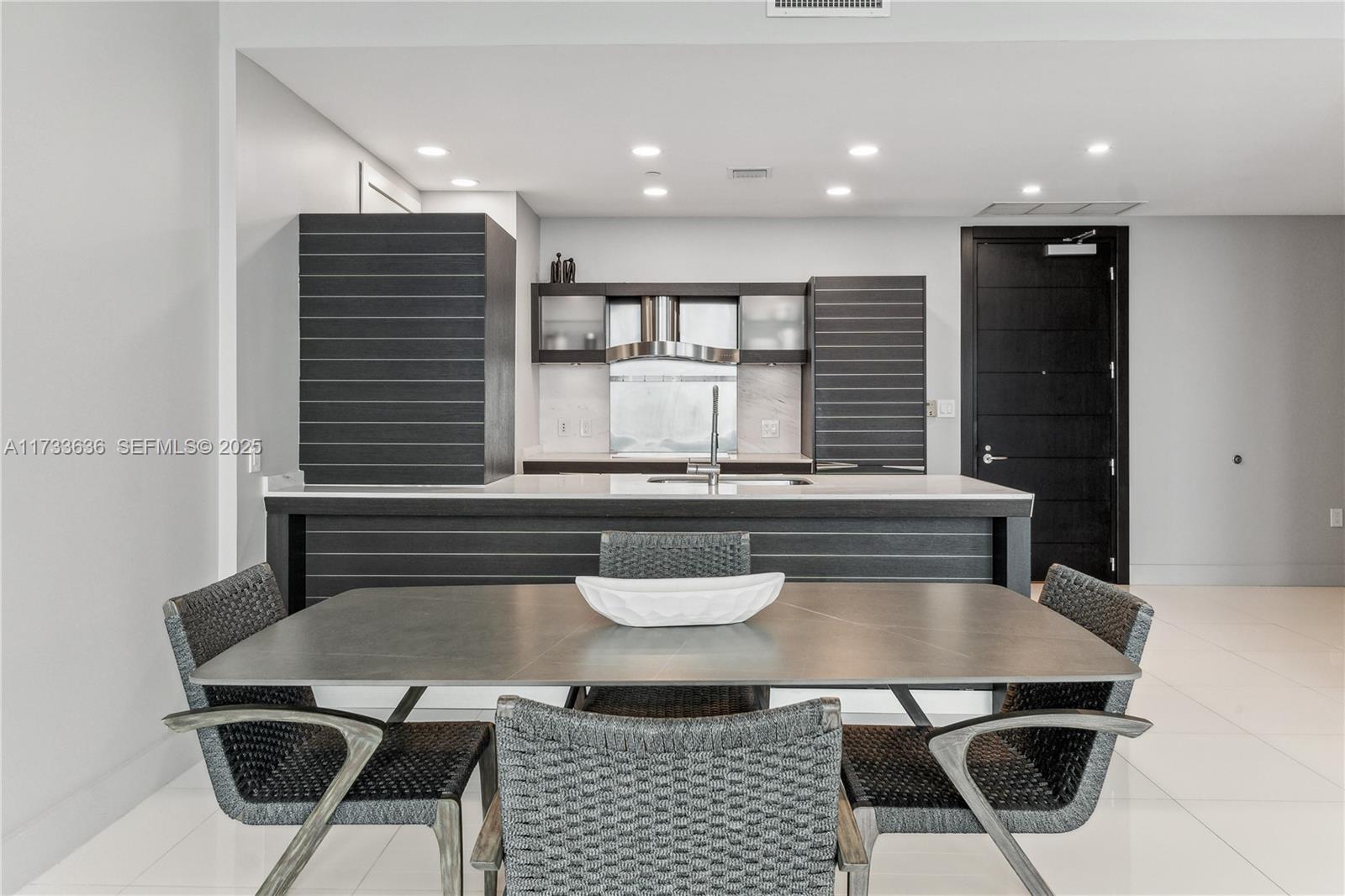 A modern kitchen features dark horizontal-slatted cabinetry and a dining area with a gray table — 200 Biscayne Boulevard Way # 4912, Miami FL 33131, MIAMI, FL