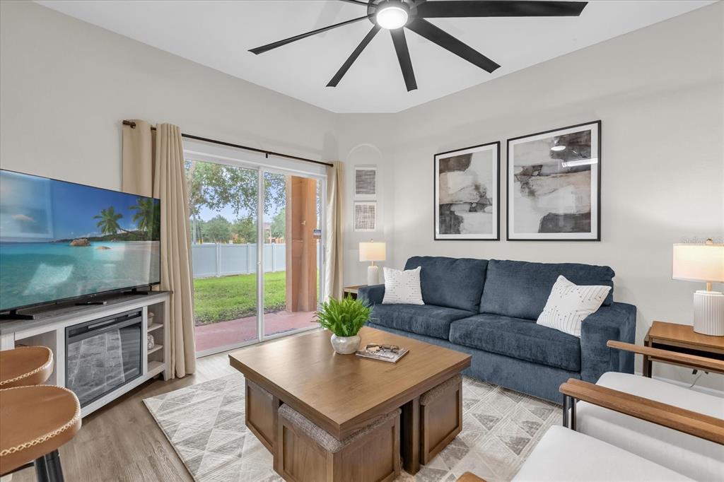 A living room features a blue sofa, a wooden coffee table, and a sliding glass door — 2020 CALABRIA AVENUE, DAVENPORT, FL