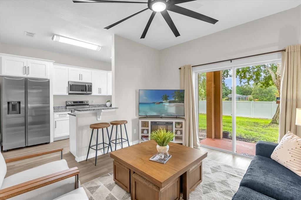 A living room with a kitchen island, stainless steel appliances, and sliding doors to a backyard — 2020 CALABRIA AVENUE, DAVENPORT, FL