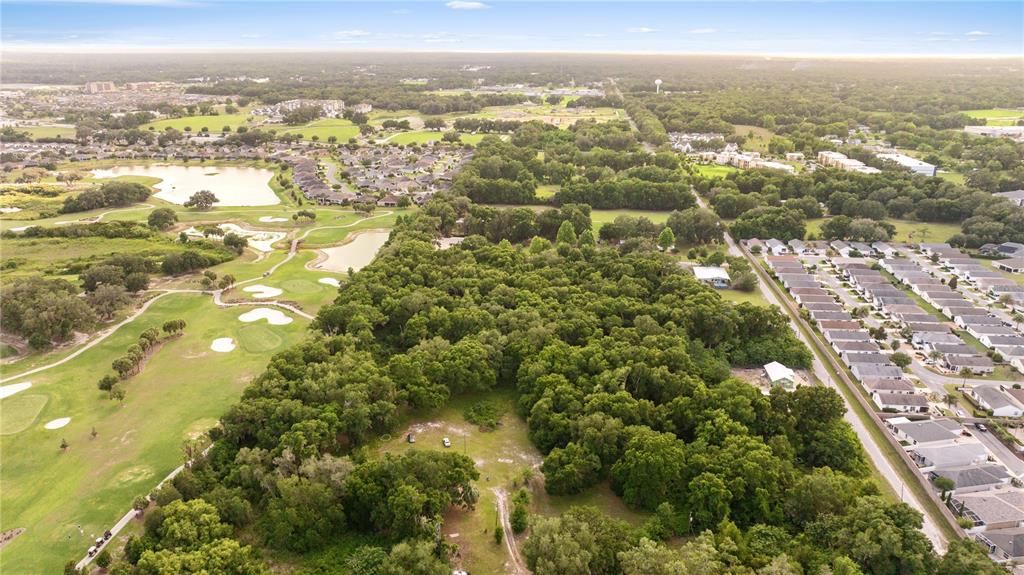 An aerial view shows a wooded lot situated between a golf course and a residential neighborhood — 0 SR 144, WILDWOOD, FL