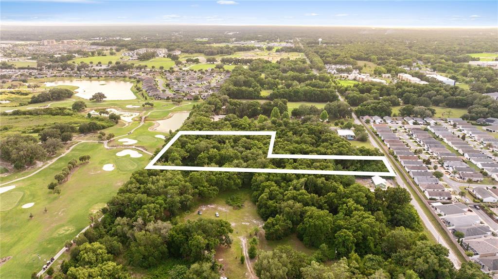 An aerial view shows a wooded lot outlined in white adjacent to a residential neighborhood — 0 SR 144, WILDWOOD, FL