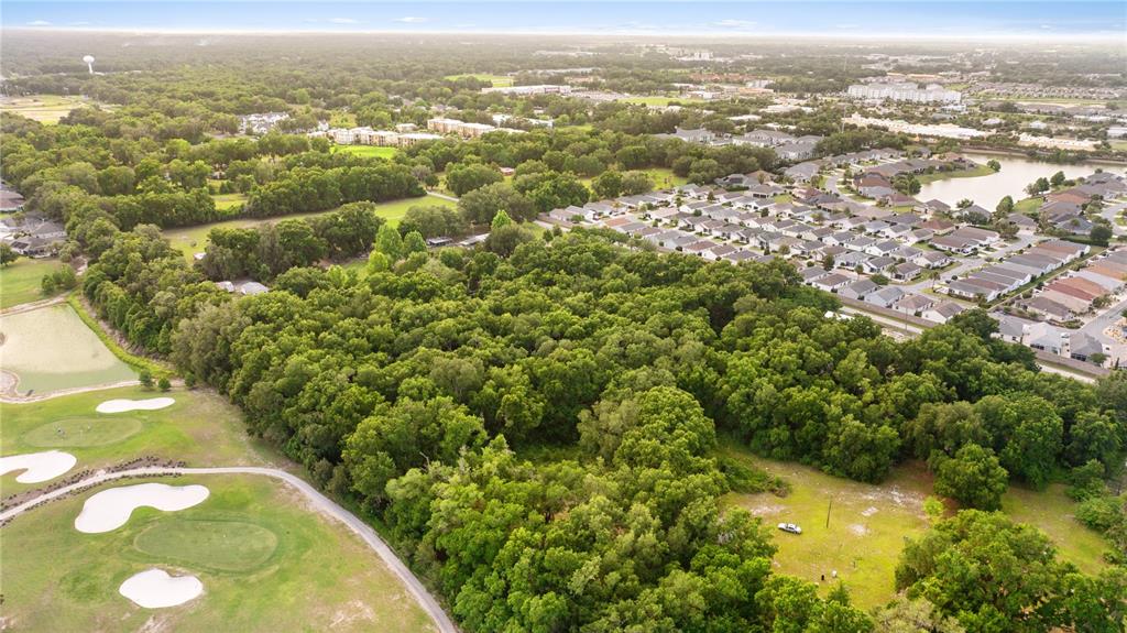 An aerial view shows a large wooded lot adjacent to a golf course and residential neighborhood — 0 SR 144, WILDWOOD, FL