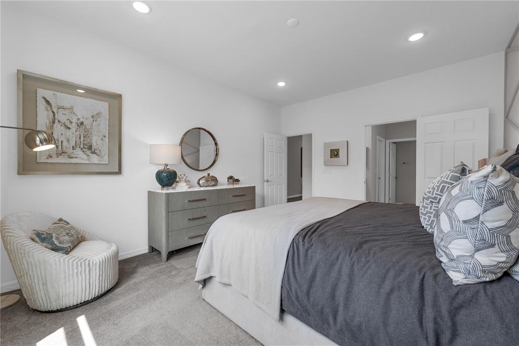 A bedroom features a gray dresser, a round mirror, a white armchair, and a bed — 1822 AMERICAN WAY, HAINES CITY, FL