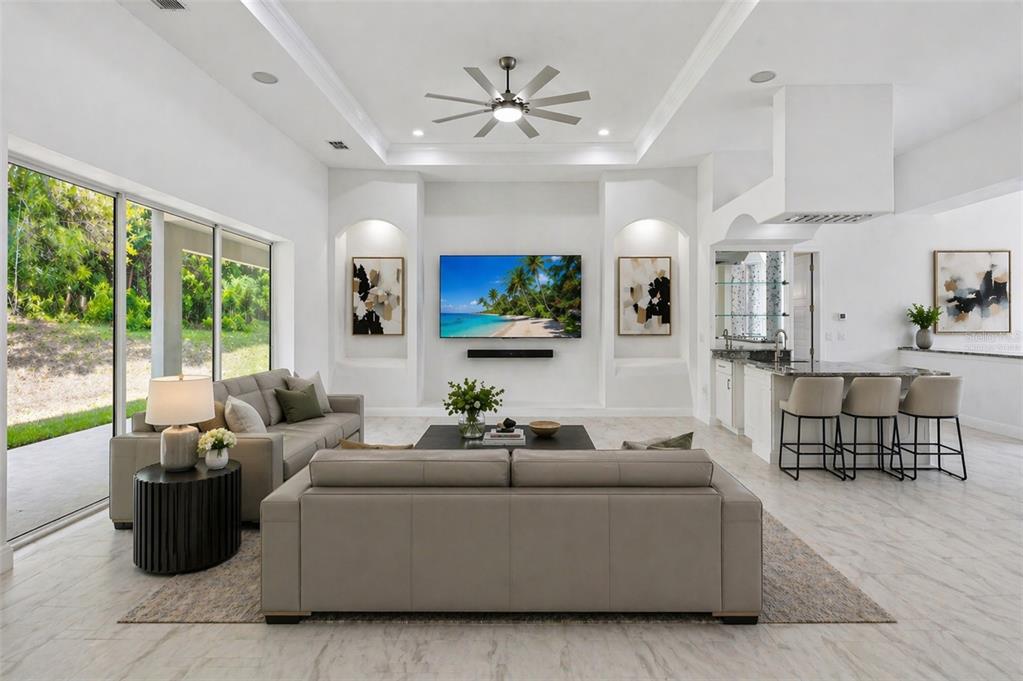 A bright living room features a large television, neutral sofas, and an adjacent kitchen bar — 421 W CHASE STREET, HERNANDO, FL