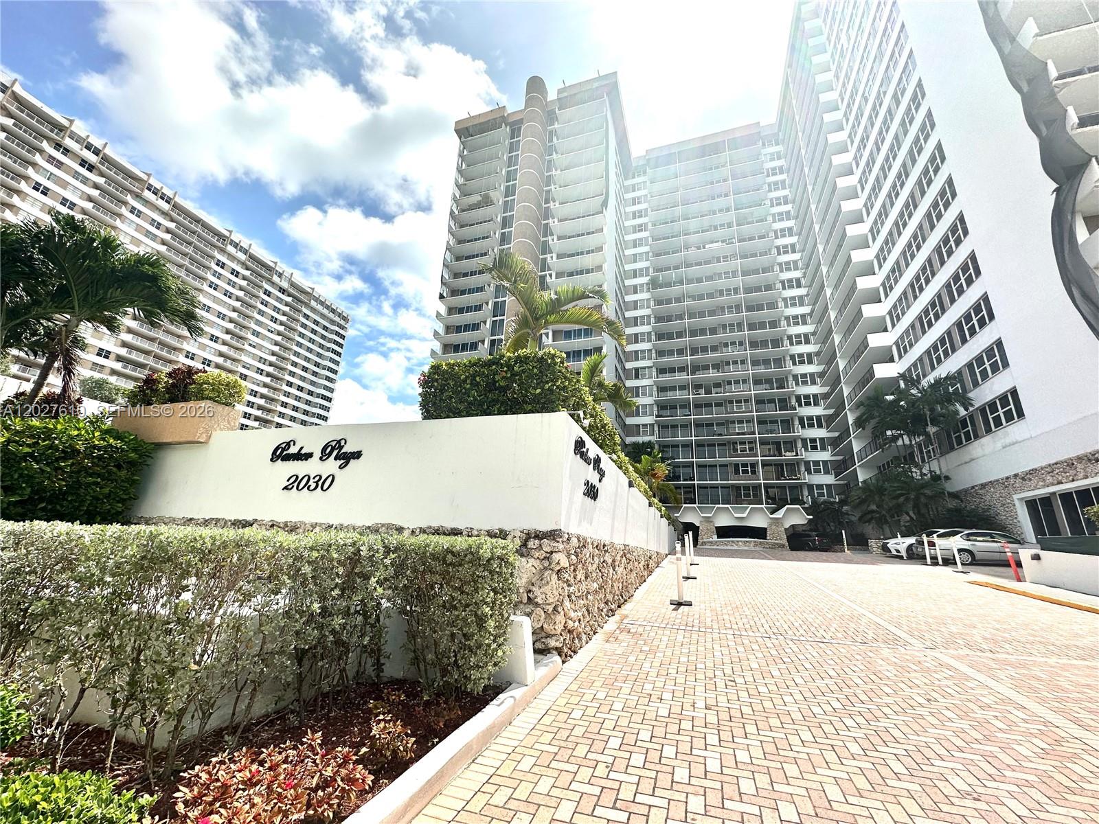 A low-angle view shows the exterior of a multi-story residential building with a paved driveway — 2030 S Ocean Dr # 1111, Hallandale Beach FL 33009, HALLANDALE BEACH, FL
