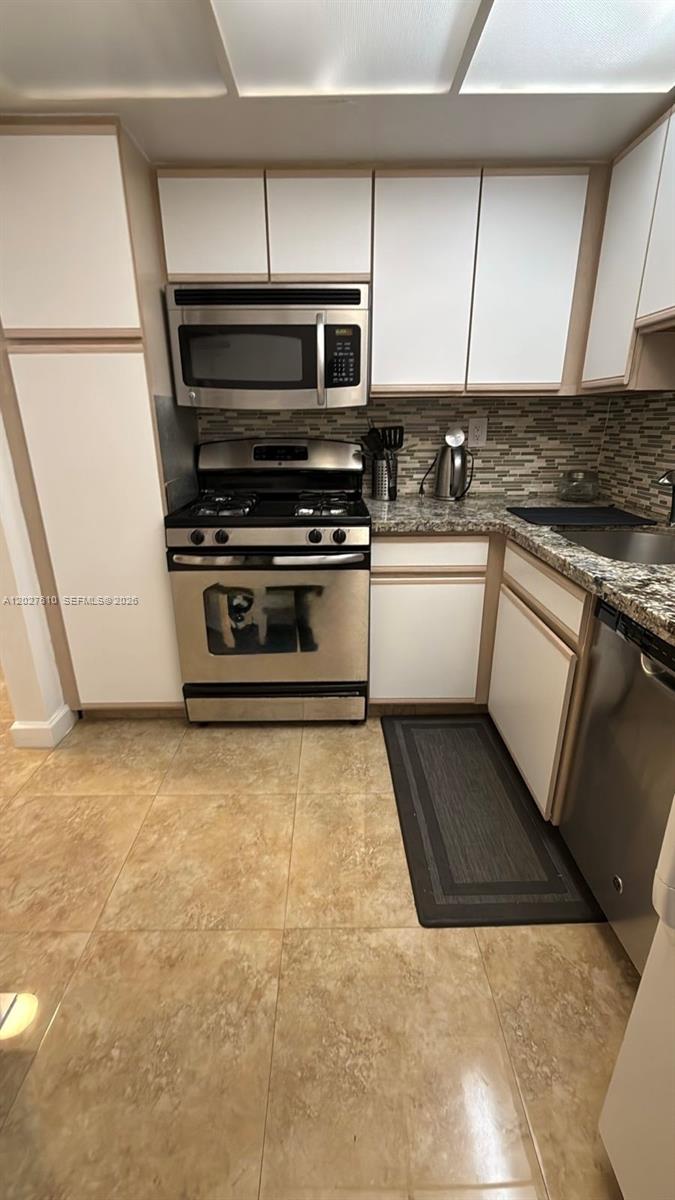 A kitchen features white cabinets, stainless steel appliances, granite countertops, and light-colored tile flooring — 2030 S Ocean Dr # 1111, Hallandale Beach FL 33009, HALLANDALE BEACH, FL