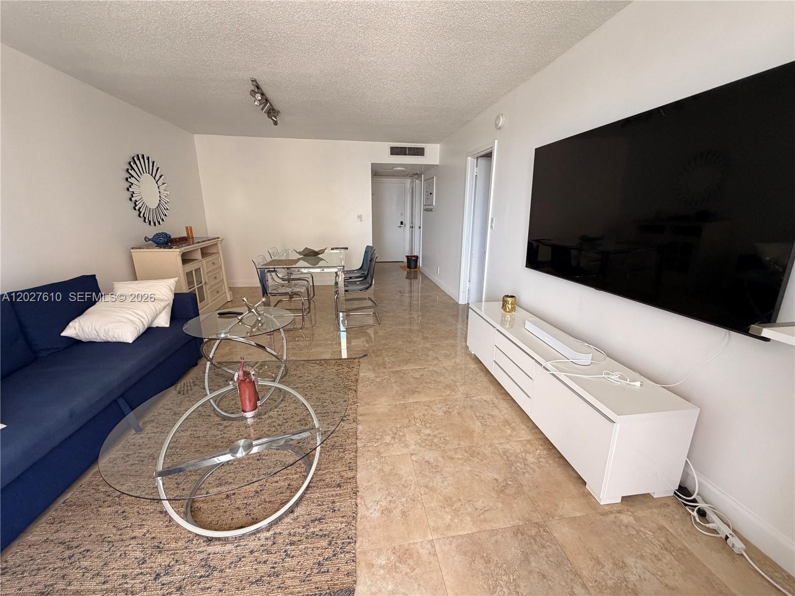 A living room features a blue sofa, glass coffee tables, a dining set, and tile flooring — 2030 S Ocean Dr # 1111, Hallandale Beach FL 33009, HALLANDALE BEACH, FL