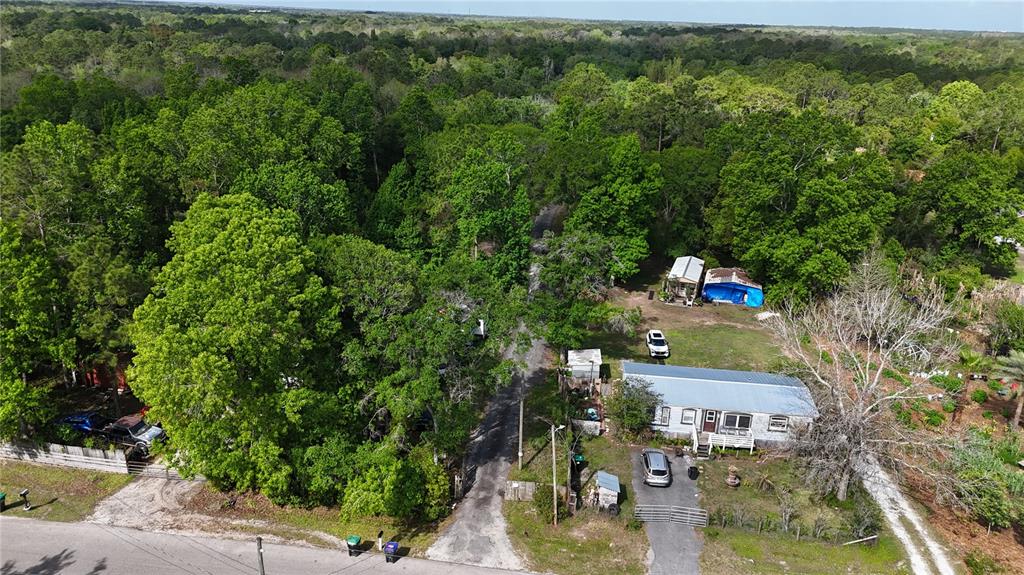 An aerial view shows a rural property with a house, outbuildings, and dense surrounding trees — 1920 10TH STREET, ORLANDO, FL