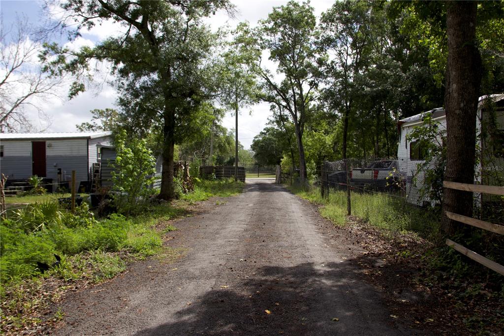 A gravel driveway leads between a mobile home and a fenced area with trees — 1920 10TH STREET, ORLANDO, FL