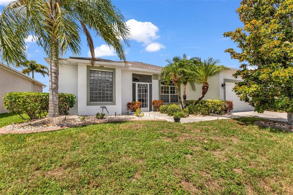 A single-story house with a glass block window, palm trees, and a front entryway — 24615 BUCKINGHAM WAY, PUNTA GORDA, FL