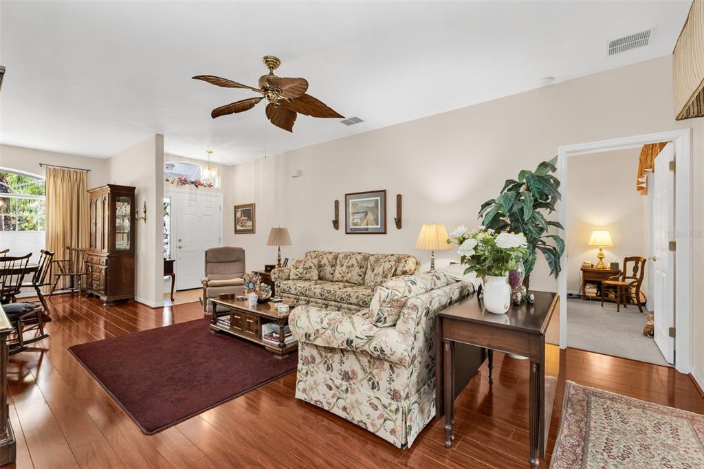 A living room features hardwood floors, a floral sofa, and a ceiling fan — 24615 BUCKINGHAM WAY, PUNTA GORDA, FL