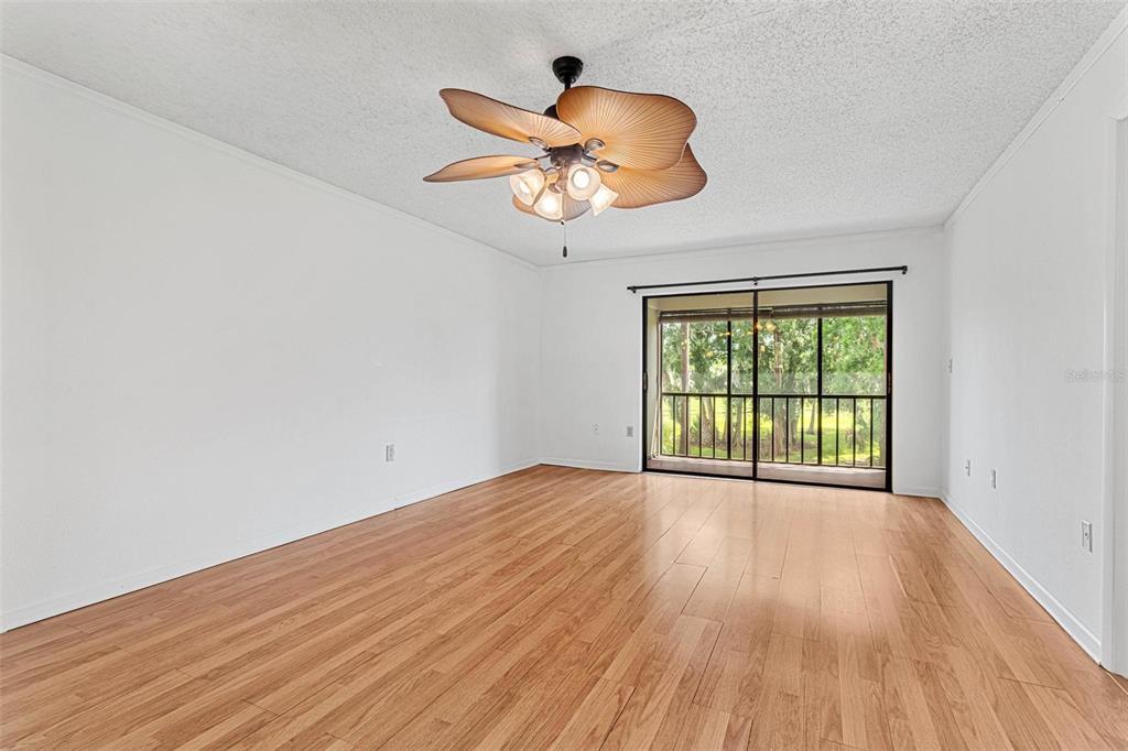 An empty room with light wood flooring, white walls, and a palm-leaf ceiling fan — 108 WOODLANDS COURT UNIT 108, OLDSMAR, FL