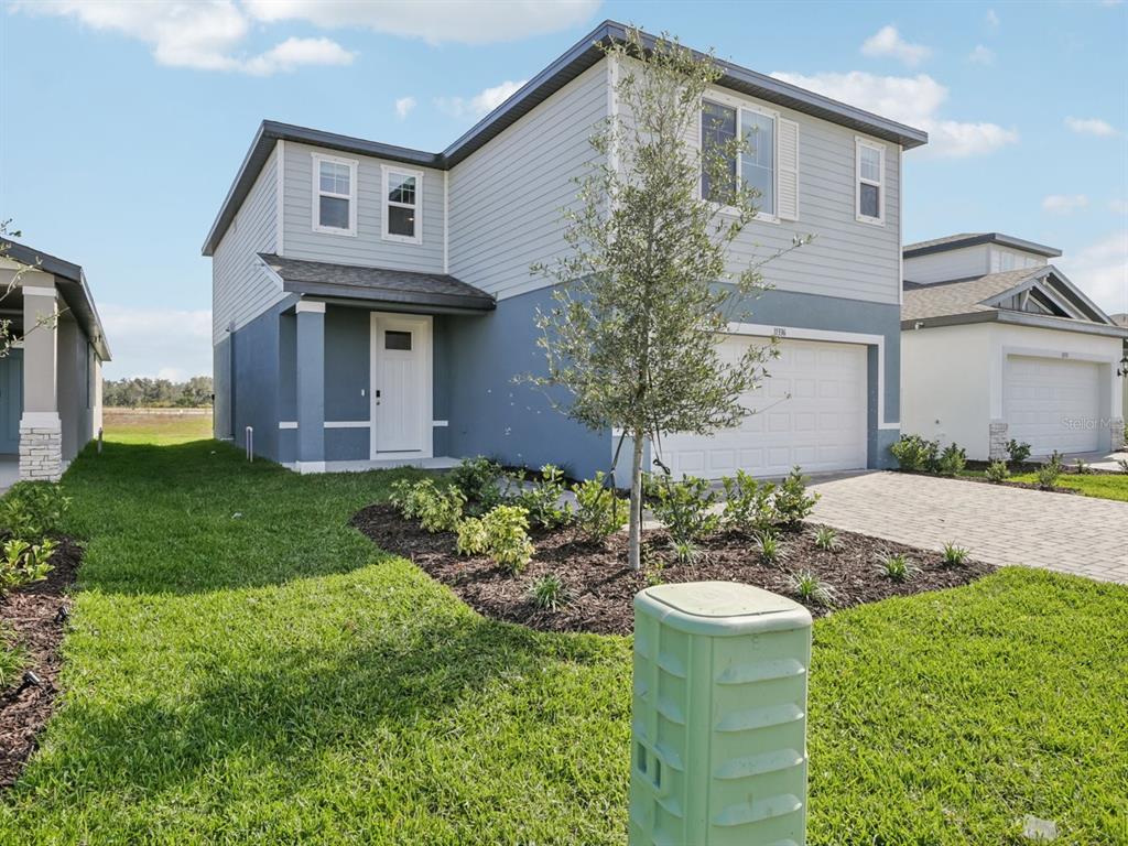 A two-story house with blue and gray siding features a front porch and garage — 11336 BELLEWOOD TERRACE, PARRISH, FL