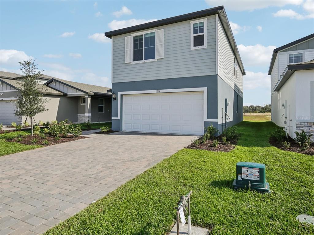 A two-story house with a white garage door, light blue siding, and a paved driveway — 11336 BELLEWOOD TERRACE, PARRISH, FL