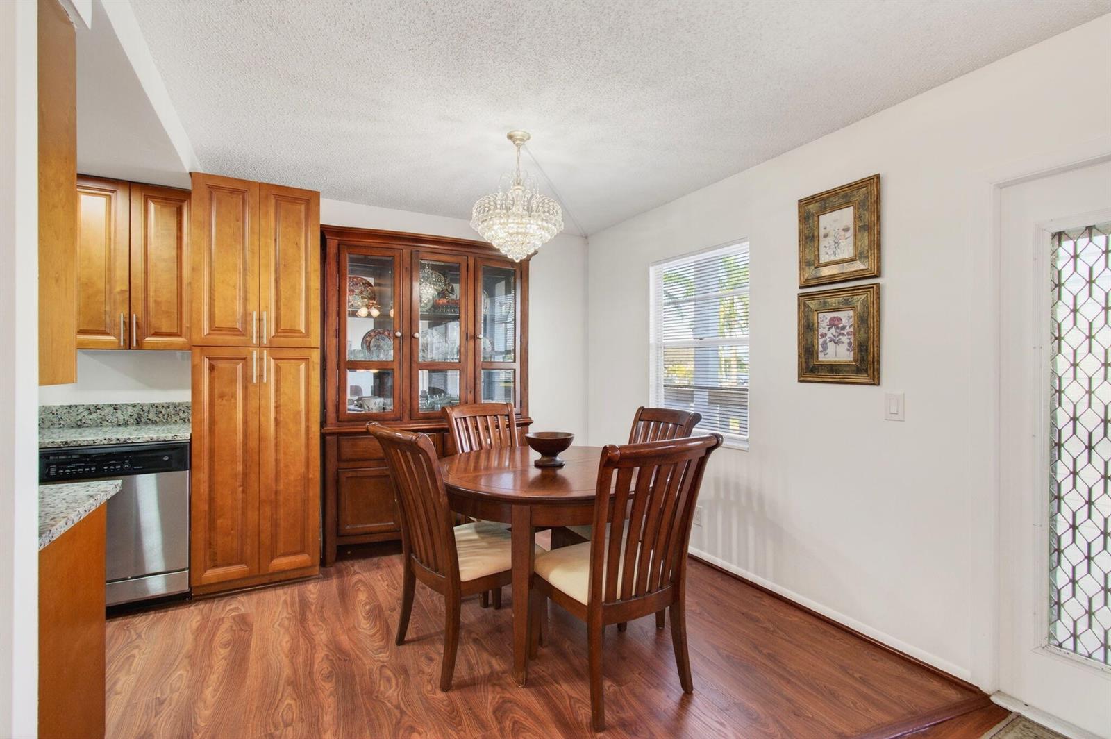 A dining area with a round wooden table, chairs, hutch, and wood-look flooring — 2035 Cornwall B, Boca Raton FL 33434, BOCA RATON, FL