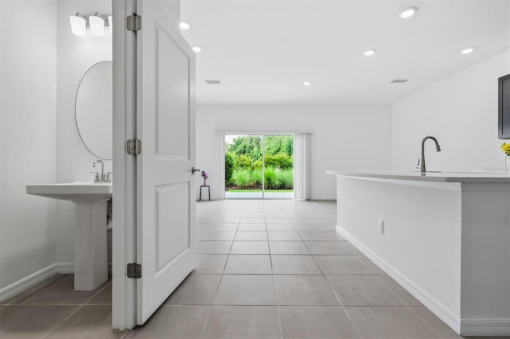 A view from a doorway into a bright room with tile floors and sliding doors — 34202 POLACCA LANE, WESLEY CHAPEL, FL