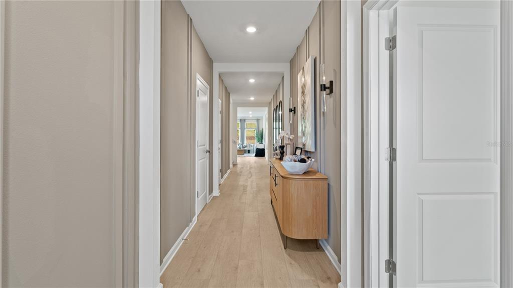 A long hallway with light wood floors, beige walls, and a wooden console table — 3121 ROCKWOOD WAY, MINNEOLA, FL