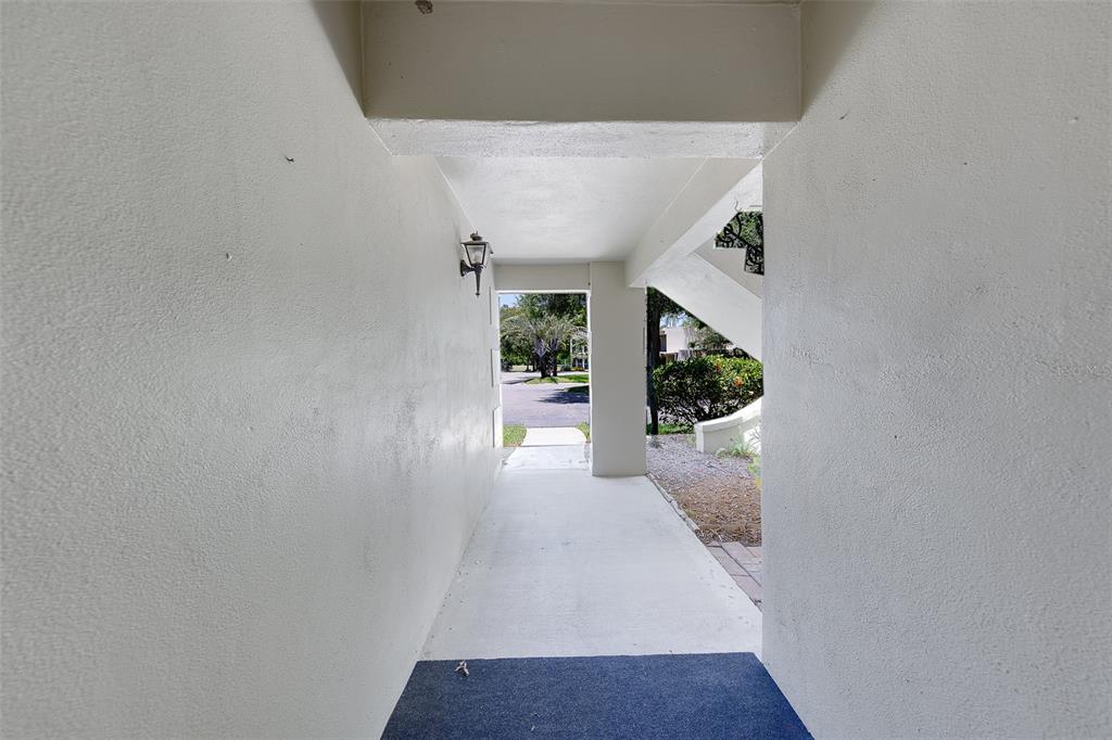 A covered outdoor walkway leads toward a parking area with stairs visible on the right — 68 COUNTRY CLUB DRIVE, LARGO, FL