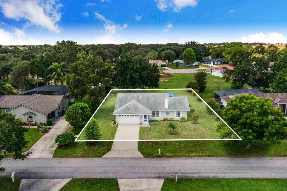 An aerial view shows a single-story house with a white exterior and a front driveway — 910 LIBERTY LANE, AUBURNDALE, FL