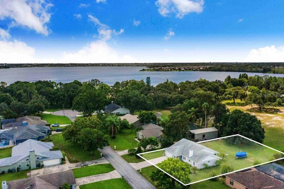 An aerial view shows a single-story house with a large yard near a lake — 910 LIBERTY LANE, AUBURNDALE, FL