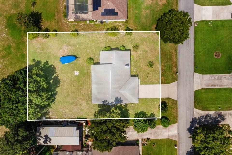 An aerial view shows a house with a large yard and a boat on a trailer — 910 LIBERTY LANE, AUBURNDALE, FL