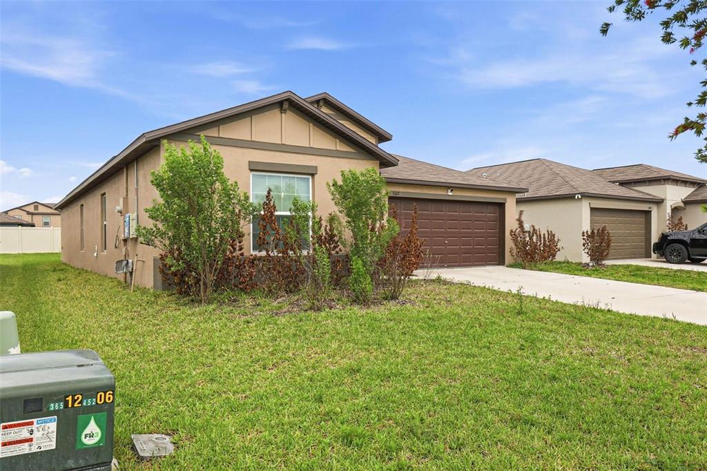 A tan single-story house with a brown garage and a green lawn in front — 3607 NATURAL TRACE STREET, PLANT CITY, FL