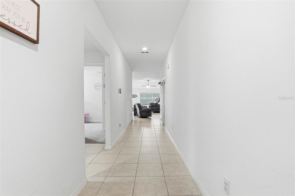 A long hallway with light-colored tile flooring leads toward an open living area — 3607 NATURAL TRACE STREET, PLANT CITY, FL