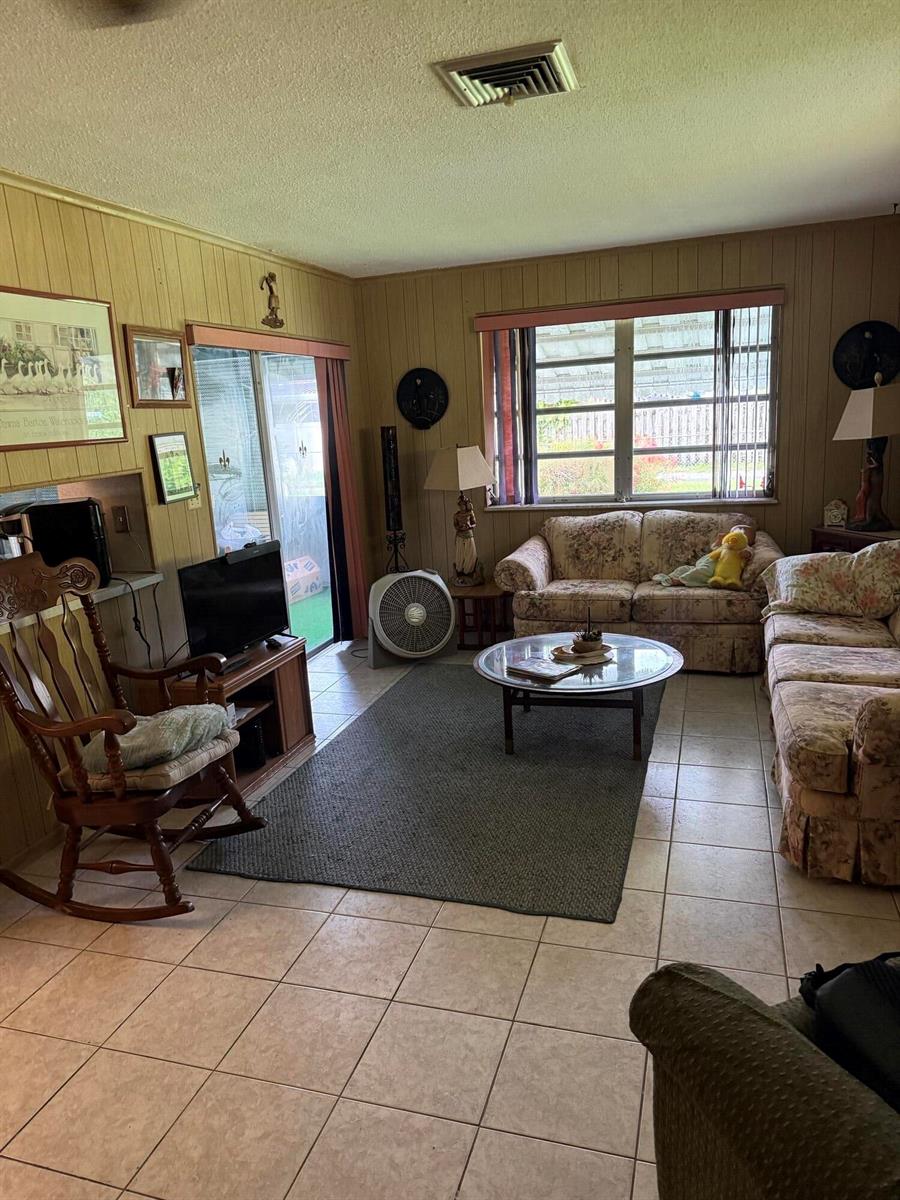 A living room features floral sofas, a rocking chair, a glass coffee table, and tile flooring — 626 S Crescent Drive, Hollywood FL 33021, HOLLYWOOD, FL