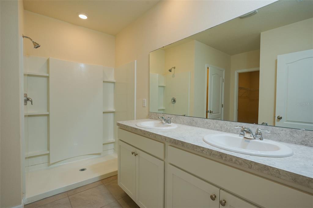 A bathroom features a double vanity with white cabinets, a large mirror, and a shower stall — 660 COTULLA DRIVE, KISSIMMEE, FL